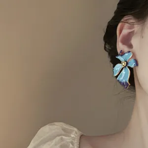 Detalle de elegantes pendientes de botón de esmalte azul con forma de flor irregular