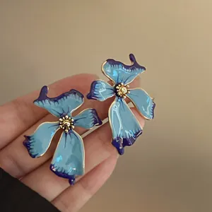 Pendientes de botón elegantes de esmalte azul con forma de flor irregular y detalles dorados