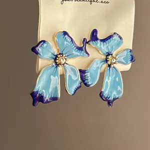 Vista macro detallada de los pendientes de botón con forma de flor en esmalte azul y lila