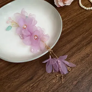 Dettaglio dell'elegante fermaglio per capelli in rete viola con nappe dorate.