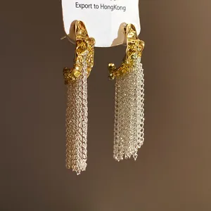 Detail view of C-shaped hoop earrings with flowing silver tassel and gold molten texture.