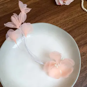 Dettaglio molletta per capelli con fiore in tulle rosa su piatto di porcellana