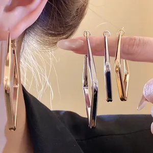 Primo piano dei dettagli di orecchini a goccia geometrici a rombo in oro e argento