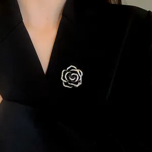 Dettaglio spilla camelia nera con zirconi incastonati su blazer nero
