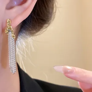 Close-up view of elegant silver and gold textured tassel drop earrings worn by model