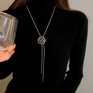 Elegante collana lunga a camelia argentata con zirconi su un maglione a collo alto nero
