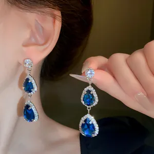 Close-up of elegant teardrop earrings featuring deep blue crystals and silver needles