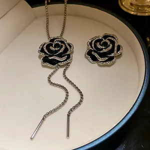 Dettaglio di set spilla e collana con camelia in smalto nero e zirconi