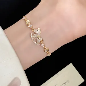 Detail shot of a 14k gold plated rocking horse charm bracelet with micro-paved zircons