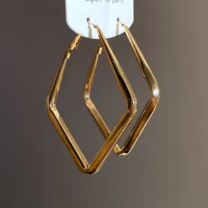 Vista macro dei dettagli degli eleganti orecchini a cerchio geometrici a rombo dorati