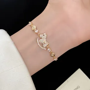 Detailed macro of 14k gold plated bracelet with zircon-encrusted rocking horse charm.