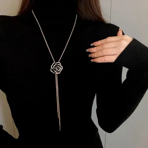 Elegante collana lunga con fiore di camelia e zirconi su dolcevita nero