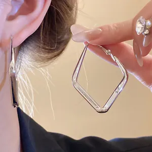 Vista dettagliata di orecchini a cerchio in argento a forma di rombo su modella elegante