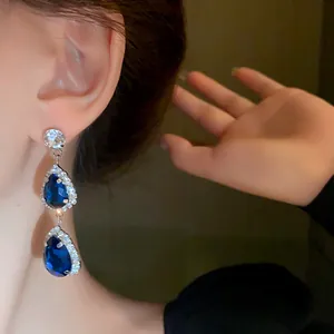 Detail of blue teardrop crystal earrings with silver needle and rhinestone halo