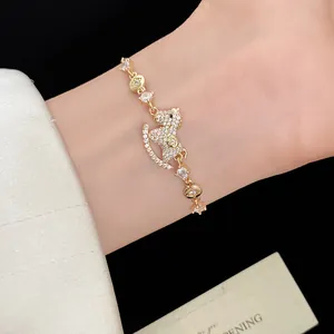 Detail shot of a luxury 14k gold plated zircon rocking horse charm bracelet worn on a wrist