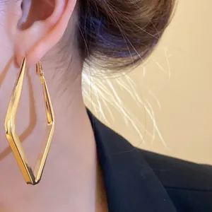 Primo piano di orecchini a rombo dorati geometrici per un look rétro minimal.