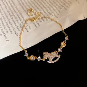 Close-up view of 14k gold plated charm bracelet with sparkling zircon rocking horse