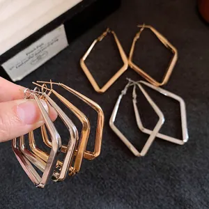Vista dettagliata di orecchini a cerchio geometrici a forma di diamante oro e argento.