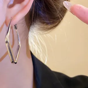 Primo piano di orecchini a cerchio geometrici a rombo in argento su una modella elegante