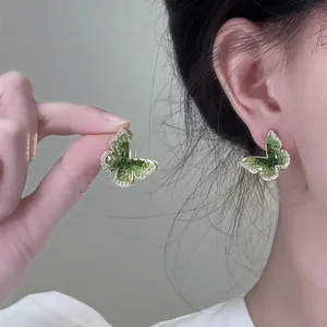 Detailed view of green butterfly stud earrings featuring a faceted center and crystal border
