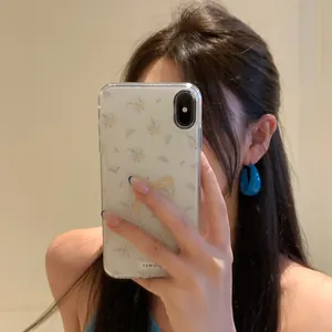 Detail shot of a vintage style blue acrylic C-shaped earring worn in a mirror selfie