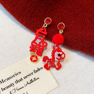 Macro view of festive red pony and Chinese character earrings with rhinestones details