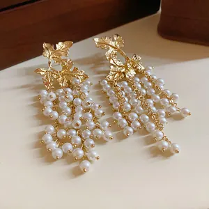 Vista molto dettagliata di eleganti orecchini a foglia d'oro con nappe di perle.