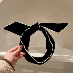 Primo piano di cerchietto con fiocco in velluto nero stile rétro con bordo in pizzo