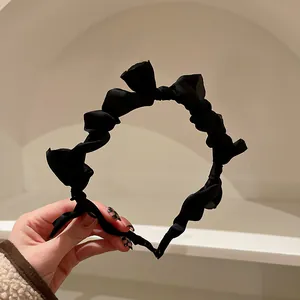 Dettaglio di un elegante cerchietto in raso nero arricciato dallo stile vintage