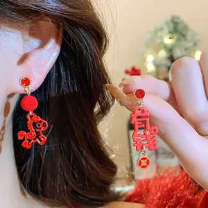 Close-up of red Chinese New Year earrings with horse and wealth character charms