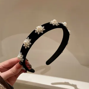 Vista dettagliata di un cerchietto in velluto nero con eleganti fiori di perle e cristalli.