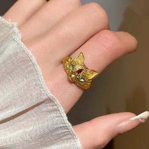 Detailed close-up view of a gold-plated fox open ring with green and red zircon stones.