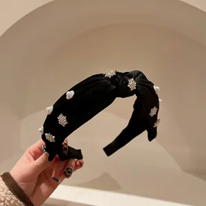 Primo piano di un cerchietto in velluto nero con decorazioni in strass e perle.