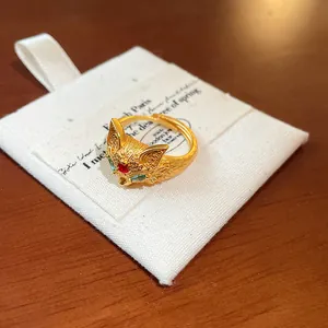 Macro detail of a 24K gold plated fox ring with colorful zirconia on a white fabric pouch.