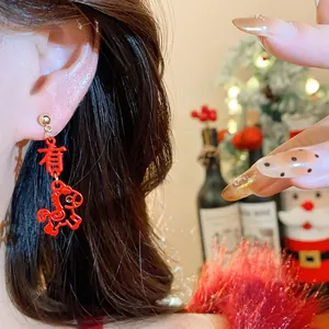 Detailed close-up of red Chinese Zodiac horse earrings on ear with festive background.