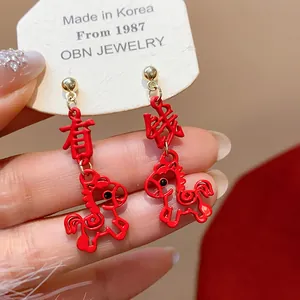 Macro view of red festive horse earrings featuring Chinese characters and gold studs.