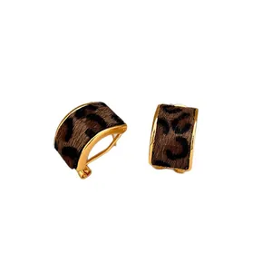 Elegant gold-tone hoop earrings featuring leopard print faux fur texture on white
