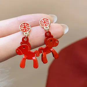 Close-up of vibrant red horse-shaped earrings with gold accents for Chinese New Year