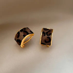 Close-up detail of vintage gold leopard print stud earrings with faux fur texture