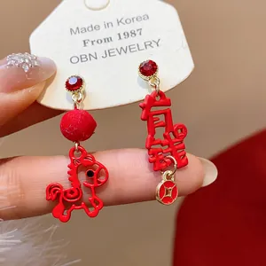 Macro view of red festive stud earrings with asymmetric pony and wealth character charm