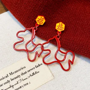 Close-up of red horse-shaped earrings with yellow Fu character studs on red fabric