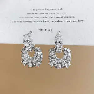 Macro detail of brilliant cubic zirconia encrusted on U-shaped gold plated earrings.