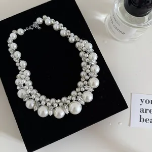 Close-up of a vintage pearl necklace with rhinestones on a black velvet display.