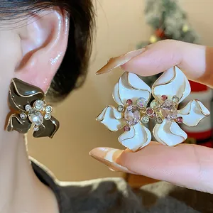 Detailed close-up of elegant floral earrings with enamel finish and sparkling crystals.