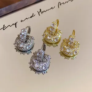 Detailed view of zircon-paved U-shape huggie earrings in gold and silver finishes