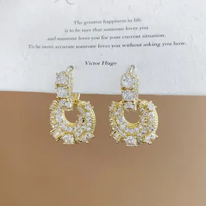 Close-up of elegant gold-plated U-shaped earrings with sparkling cubic zirconia stones