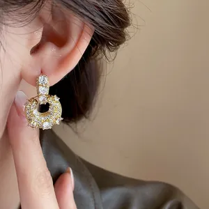 Detailed macro view of luxury gold plated zirconia U-shape earrings worn on a model's ear