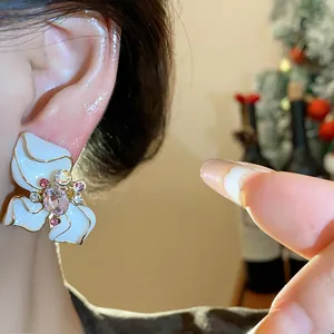 Detailed macro view of elegant vintage-style enamel flower stud earrings with pink rhinestones