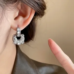 Close-up detail of luxury gold-plated zircon U-shaped bag earrings worn on an ear