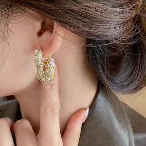 Close-up of elegant gold-plated bag-shaped hoop earrings with sparkling cubic zirconia stones